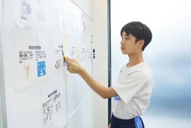 ホワイトボードにイラストを描く少年